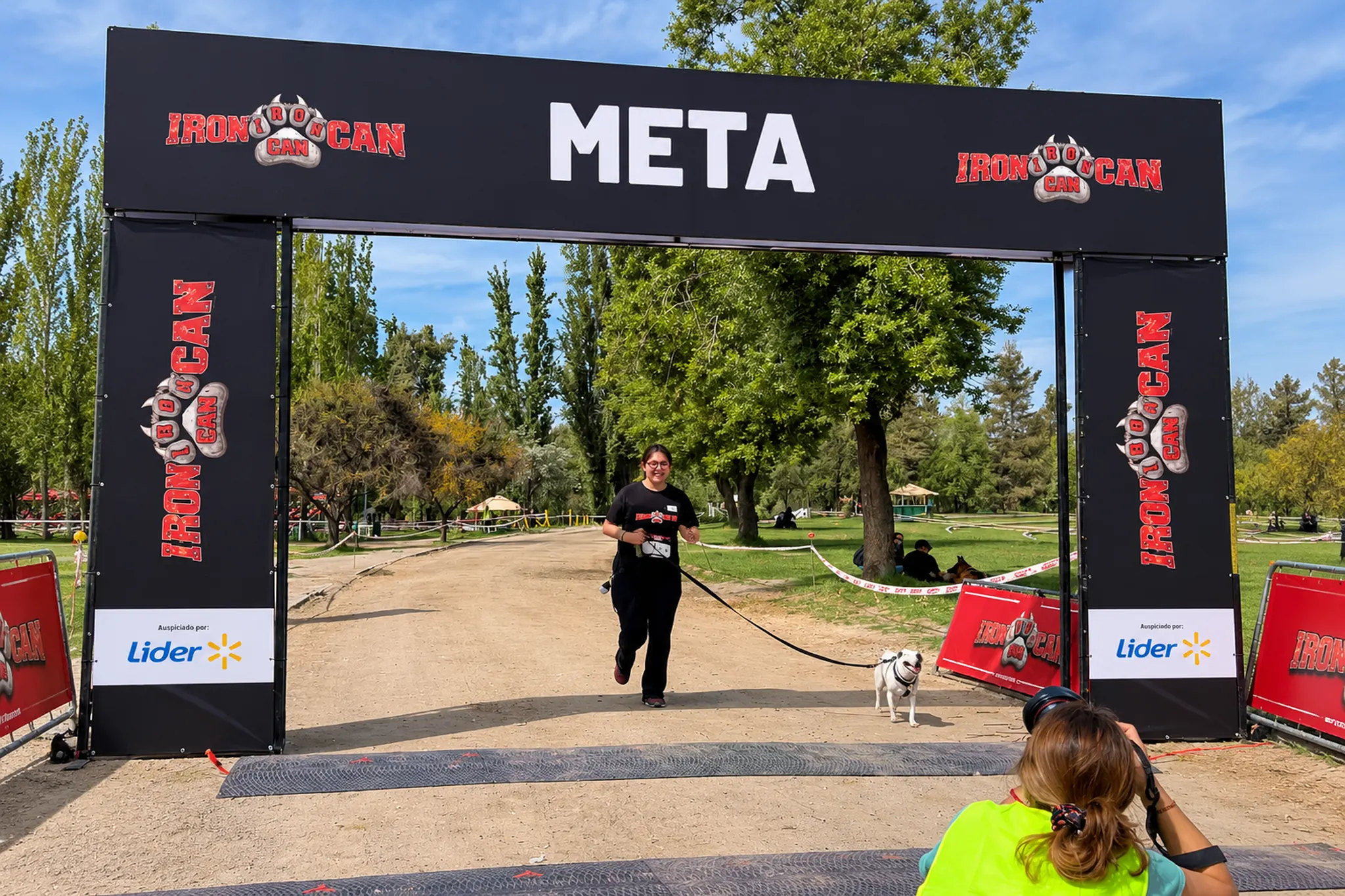Participante de IronCan Chile 2026 llegando a la meta con su perro bajo el arco de la carrera